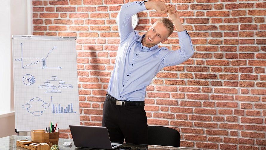 Business-Mann steht vor seinem Laptop und streckt sich Business-Mann steht vor seinem Laptop und streckt sich